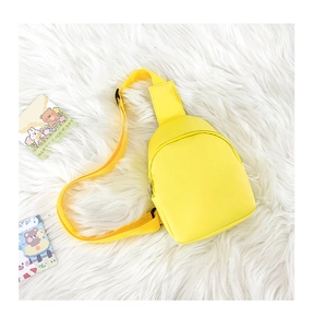 Detail of yellow kids chest bag with adjustable strap on white faux fur background