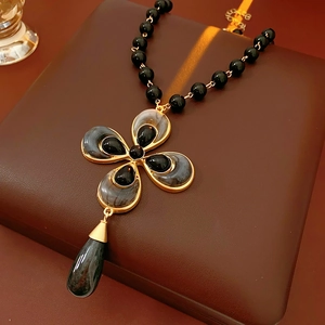 Detail of vintage flower and teardrop necklace with black beads and gold metallic frame