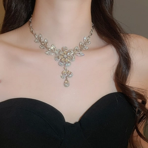 Detailed close-up of a silver flower necklace with sparkling diamonds and tassel pendant