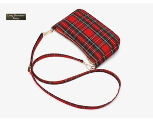 Detail view of red plaid baguette bag with adjustable long shoulder strap and gold hardware