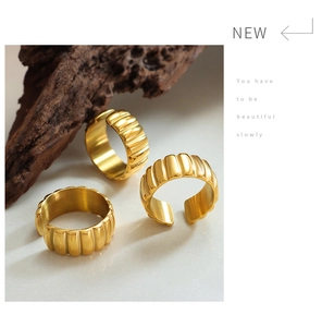 Detail of 18K gold-plated stainless steel rings with ribbed texture on wooden branch