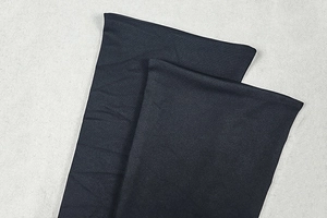 Detailed close-up of black knitted fabric texture and hem stitching on a slim-fit dress