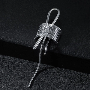 Close-up of silver metal ear cuff featuring bow design and long snake chain tassel