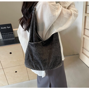 Detail view of large dark grey washed denim tote bag with external button pocket