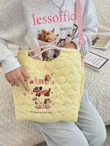 Quilted yellow shoulder bag with dog embroidery and pink adjustable strap in lifestyle setting