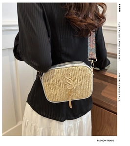 Detail of woven straw crossbody bag with colorful wide strap and golden metal logo