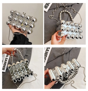 Detail of silver metallic sphere evening bag with mirror finish and beaded chain strap