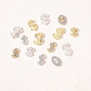 Detailed view of dollar sign nail charms in gold and silver with luxury rhinestone inlays
