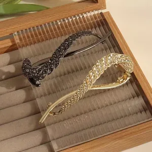 Detail of luxury rhinestone banana hair clips with twisted rope texture in gold and black