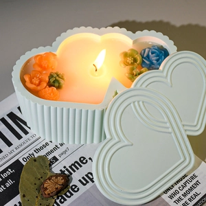 Detail of mint green heart-shaped candle jar with striped texture and floral wax decor