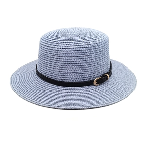 Detail of light blue straw hat featuring flat top and black leather band with gold buckle