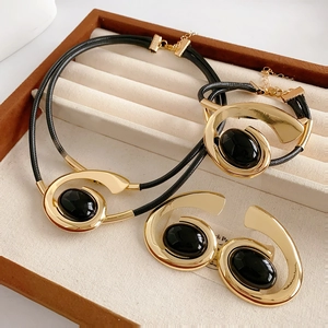 Detailed set of gold spiral necklace, bracelet, and earrings with black oval stones