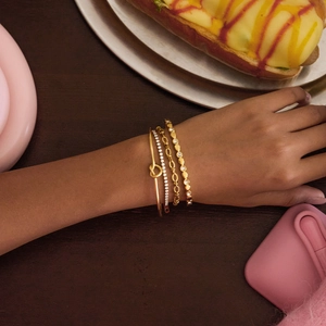 Set of four 18K gold plated stainless steel knot bracelets and rhinestone bangles on wrist