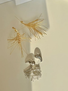 Layout artistico di orecchini a nappa ad ago di pino in finiture oro e argento