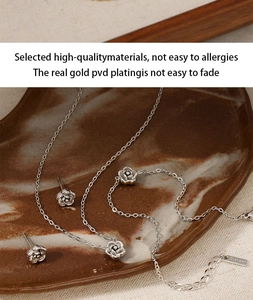 Detailed view of silver rose jewelry set with necklace and earrings on marble tray
