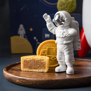Astronaut figurine with golden mooncakes on a wooden tray in a space themed gift box