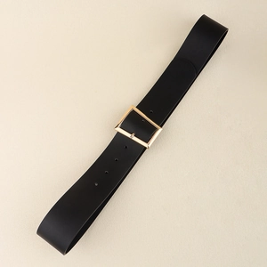 Detail of a black wide belt featuring a polished golden rectangular metal buckle