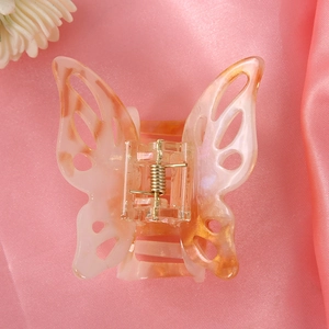 Macro shot of marble textured pink butterfly hair claw clip on soft silk fabric