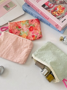 Floral and polka dot fabric makeup bags and coin purses on a clean aesthetic desk