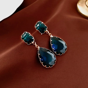Macro detail of leaf drop earrings with blue zircon crystals and gold plated finish