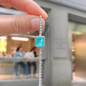 Macro shot of an elegant green rectangular gemstone necklace with a sparkling diamond chain