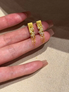 Détail de boucles d'oreilles épi de blé dorées avec zircons et pampilles à fines chaînes