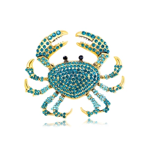 Exaggerated crab brooch with sparkling blue rhinestones on a gold alloy metal base