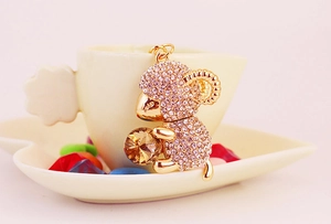 Close-up of golden zodiac sheep keychain with pink crystals and large gem detail