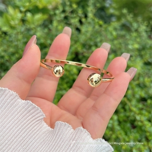 Dettaglio di un bracciale rigido placcato oro 18K con doppie sfere lucide alla luce