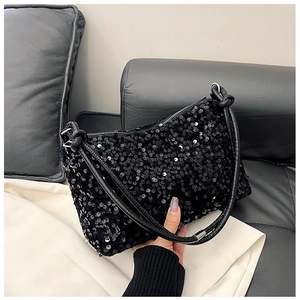 Close-up of sparkling black sequin baguette bag with leather strap and silver metal rings