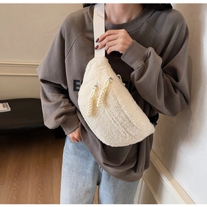 Detail of off-white plush crossbody bag showing soft texture and woven zipper pullers
