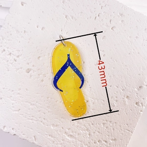 Detail shot of 43mm yellow acrylic flip-flop pendant with silver glitter on stone surface