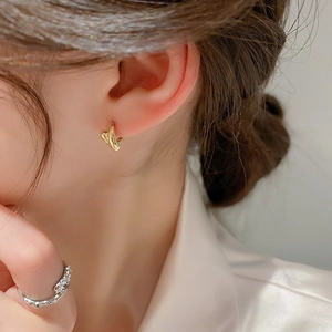 Detail view of model wearing elegant golden twisted hoop earrings with a modern design