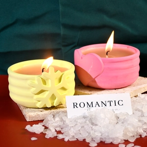 Dettagli di candele natalizie accese con motivi a rilievo di fiocchi e cuori
