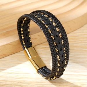 Close-up of black braided leather bracelet with gold beads and magnetic clasp detail