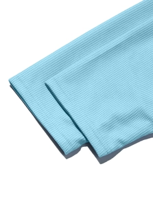 Close-up of light blue polo shirt cuff showing premium waffle knit texture and stitching