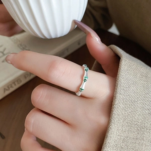 Detailed view of silver bamboo joint ring with green enamel leaves on a model's hand