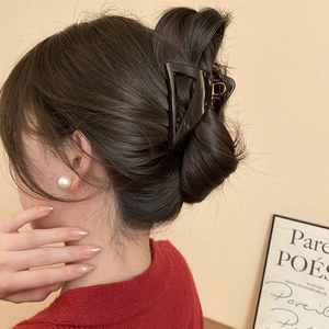 Close-up of a large glossy brown triangle hair claw clip on a model's hair