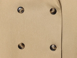 Macro view of khaki blazer sleeve showing four dark brown tortoiseshell buttons and twill fabric