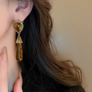Close-up of vintage resin water drop earrings with amber stones and shiny rhinestones