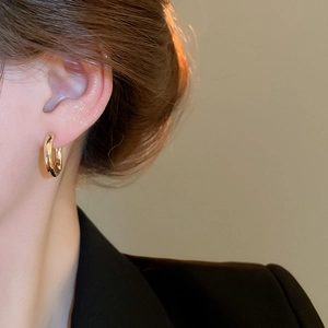 Close-up of elegant gold round hoop earring worn by a model with warm lighting