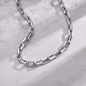 Polished silver rectangular link chain for men on textured grey background