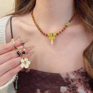 Close-up of beaded necklace with fairy pendant and multi-color gemstone bracelet on model