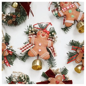 Close-up of gingerbread man ornament with mini pine wreath and festive golden bells