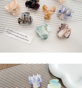 Close-up of small acrylic hair claws with elegant marble patterns in various colors