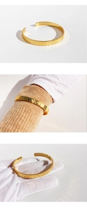 Dettaglio di un bracciale a fascia aperta in oro con texture a righe verticali