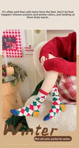 Close-up of Christmas mid-calf socks with red argyle pattern and Santa Claus motif