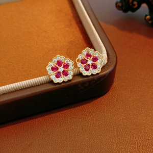 Macro view of flower stud earrings with red pear-cut gems and white zircon details