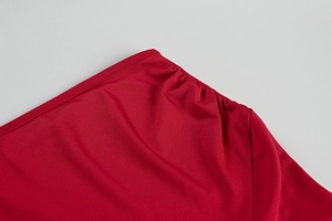 Detail shot of red ruched fabric showing elegant pleated texture on a slim-fit dress