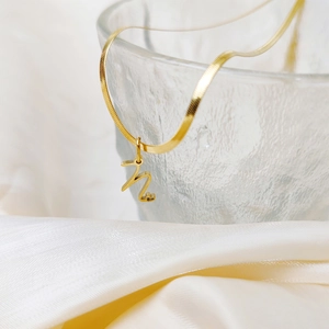 Detailed view of a gold stainless steel flat snake chain necklace with letter N pendant.